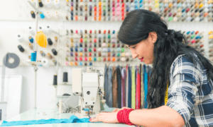 Woman sewing fabric using a sewing machine in a colorful thread shop.
