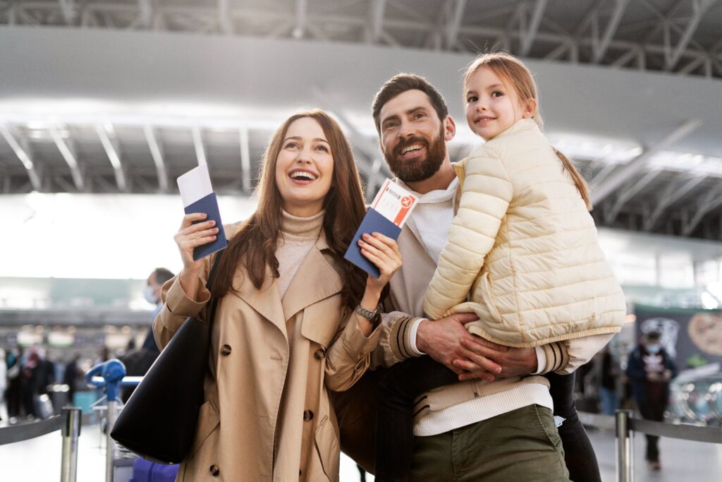 Smiling family at airport holding passports and boarding passes.